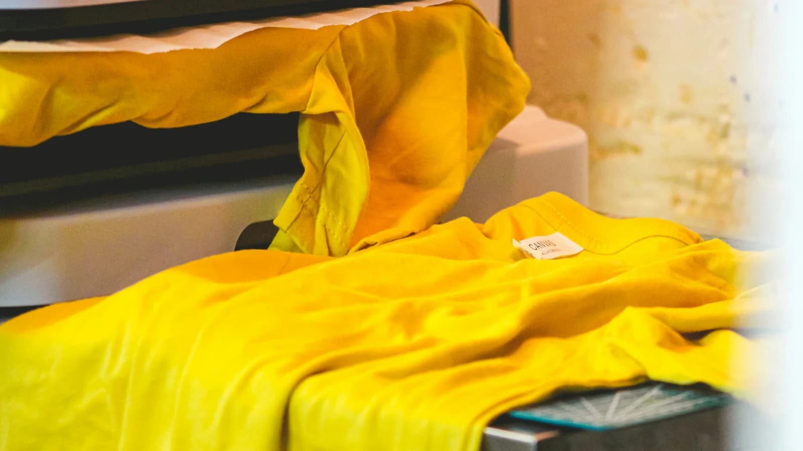 A bright yellow T-shirt positioned beneath a commercial heat press