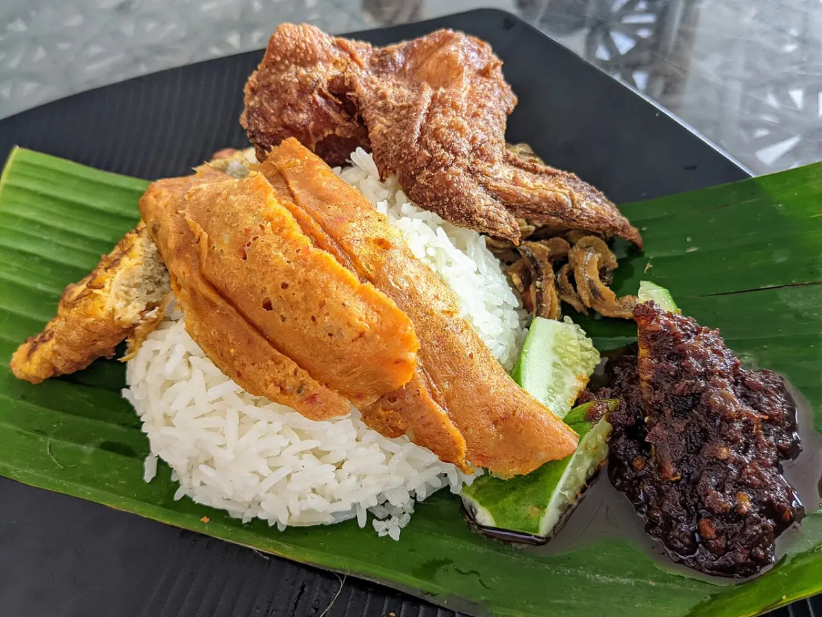 Nasi lemak on banana leaf with fried chicken, otak-otak, sambal, cucumber and anchovies