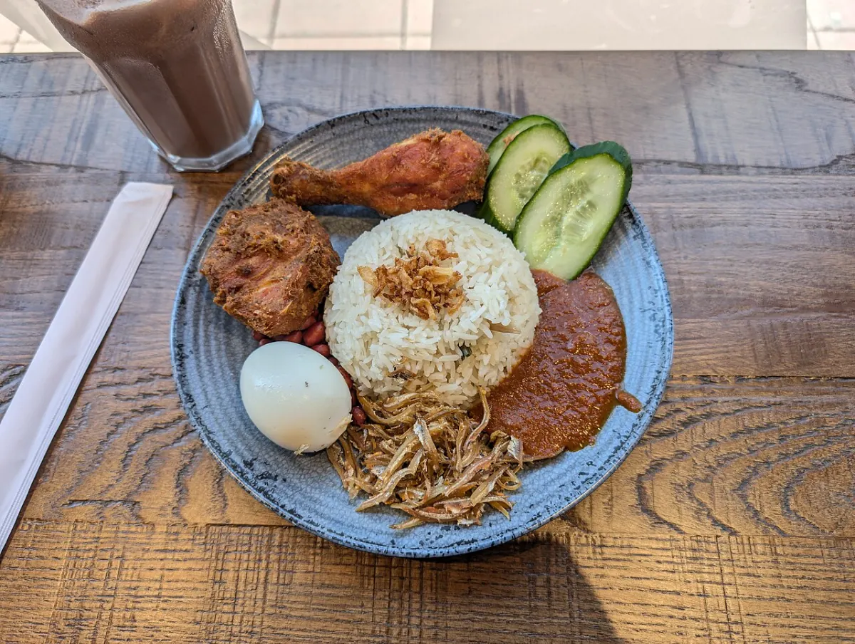 Nasi lemak with two pieces of fried chicken, coconut rice, sambal, anchovies, peanuts, egg and cucumber