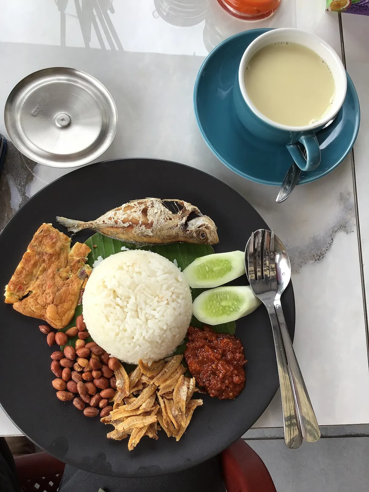 Traditional nasi lemak with coconut rice, sambal, egg, fried fish, peanuts and anchovies